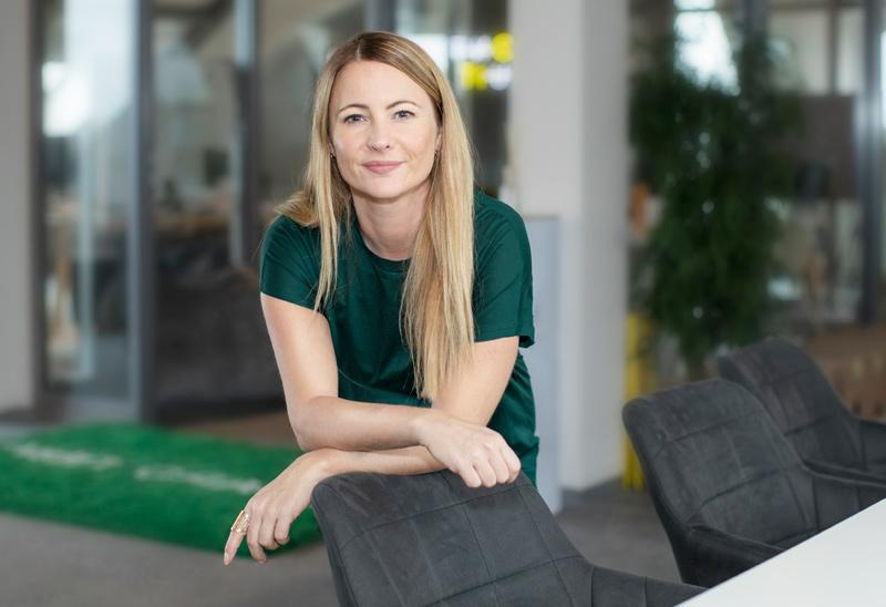 Abbildung einer stehenden Frau im grünen Kleid hinter einem dunklen Bürostuhl